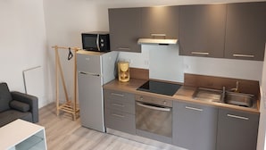 Eine moderne Küche mit grauen Schränken, einem eingebauten Ofen, einer Kaffeemaschine und einer Mikrowelle auf einem Holzboden.