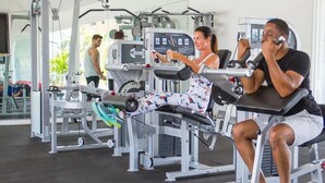 Uma academia com diversos equipamentos de exercícios, incluindo uma máquina de leg press e uma de supino.