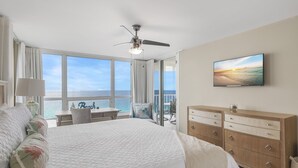 Une chambre d’hôtel avec un grand lit, un ventilateur de plafond, une télévision, un bureau et une vue sur l’océan.