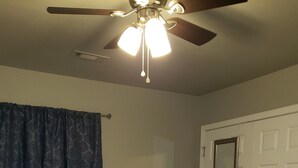 A bedroom with a bed, a ceiling fan, a door, and a window with curtains. - Northwest Arkansas Adventures- Beautiful Condo, with Two Master Bedrooms   (Fayetteville)