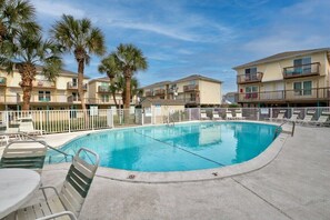 A swimming pool with lounge chairs and palm trees, surrounded by multi-story buildings with balconies. - Amazing 2BR Gulf View Condo | Private Beach Access (Gulf Shores)