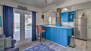 A kitchen with blue cabinets, a stainless steel refrigerator, and a bar area. - Private Pool/Pier - Beautiful Bayfront Property! (Gulf Shores)