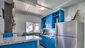 A kitchen with blue cabinets, a granite countertop, and a stainless steel refrigerator. - Private Pool/Pier - Beautiful Bayfront Property! (Gulf Shores)
