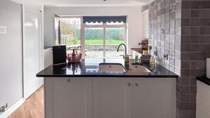 Eine Küche mit schwarzem Arbeitsplatz, weißen Schränken, einer Spüle und einem Fenster mit Blick auf einen Garten.