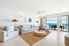 A modern living room with a sofa set, a coffee table, and a view of the ocean. - Luxury Stay – La Mer Noosa Apartment 09 (Noosa Heads)