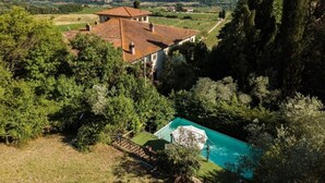 Eine Villa mit Ziegeldach, umgeben von üppiger Vegetation und einem Swimmingpool.