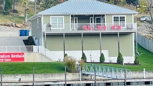 A two-story building with a balcony, a dock, and a sign for vacation rentals.
