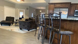 A modern kitchen with a bar area, wooden cabinets, and a large refrigerator.