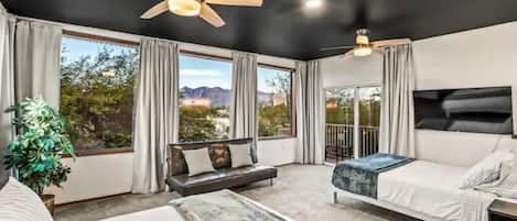 Une chambre d’hôtel moderne dotée d’un grand lit, d’un canapé, d’un bureau et d’un balcon offrant une vue sur les montagnes.