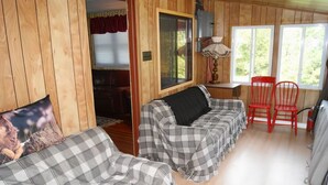 Una habitación acogedora con dos sofás a cuadros, una silla roja y una ventana con vistas al verdor.