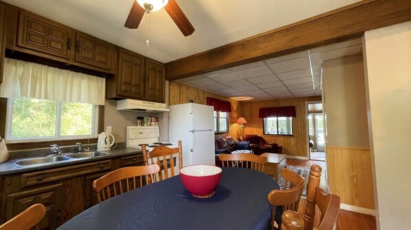 Une cuisine avec des meubles de rangement en bois, un réfrigérateur, un évier et une table à manger avec des chaises.