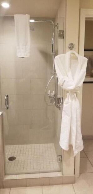 Shower area features a glass door, a towel and bathrobe for convenience.