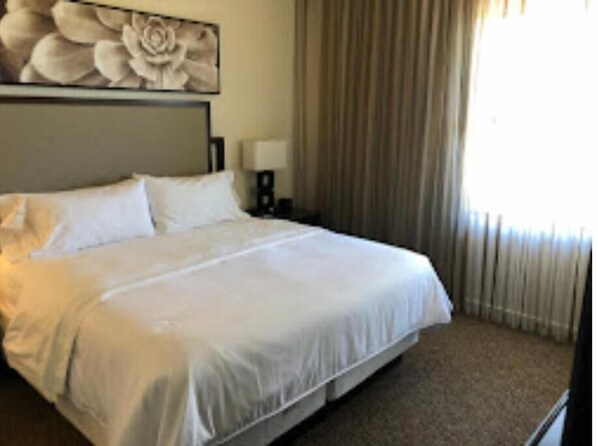 Relax in a serene space with a large bed, a headboard featuring a floral design, and a bedside table with a lamp.