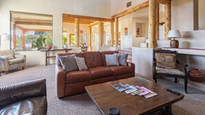 A spacious living area with a brown leather sofa, a wooden coffee table, and a patterned armchair. - Fabulous Luxury Home on Quiet 2 acres (Tucson)