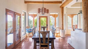 A dining area with a wooden table and chairs, large windows, and a ceiling fan. - Fabulous Luxury Home on Quiet 2 acres (Tucson)
