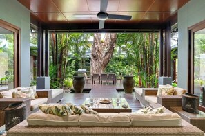 Spazio interno moderno con un'ampia pianta, una ventola a soffitto e un'area pranzo con tavolo e sedie.