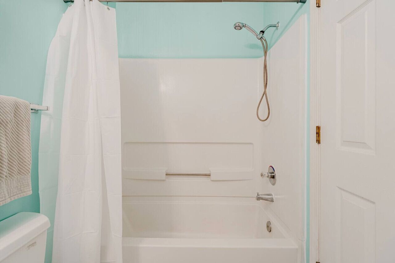 A bathroom with a shower, a towel rack, and a door.