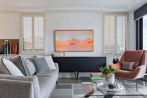 A modern living room with a sofa, armchair, and a coffee table with a plant.