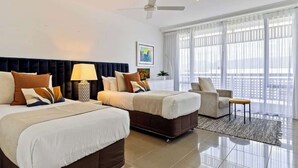 A hotel room with two beds, a ceiling fan, a large window with curtains, and a view of the city.