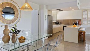 A modern kitchen with a central island, stainless steel appliances, and a glass dining table.