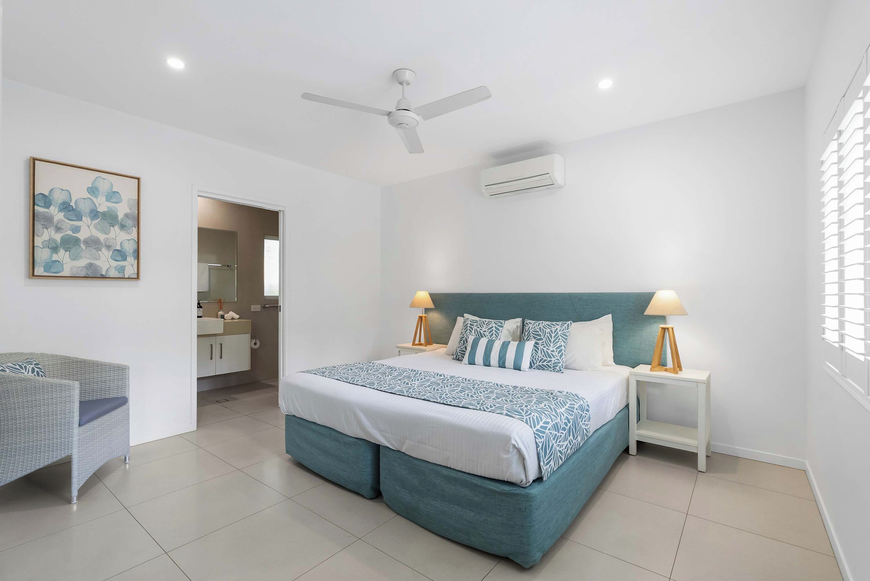 A modern bedroom with a bed, bedside tables, a ceiling fan, and an air conditioning unit.