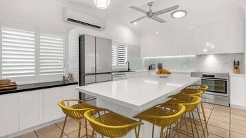 Une cuisine moderne dotée d’un grand îlot central, de meubles blancs et d’un four encastré.