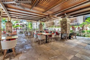 Un'area patio esterna con pavimento in pietra, mobili in vimini e struttura del soffitto in legno.