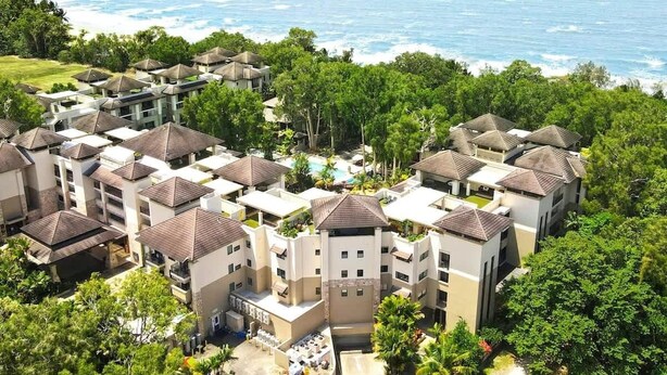 Un complexe hôtelier comprenant plusieurs bâtiments, une piscine et offrant une vue sur l’océan.