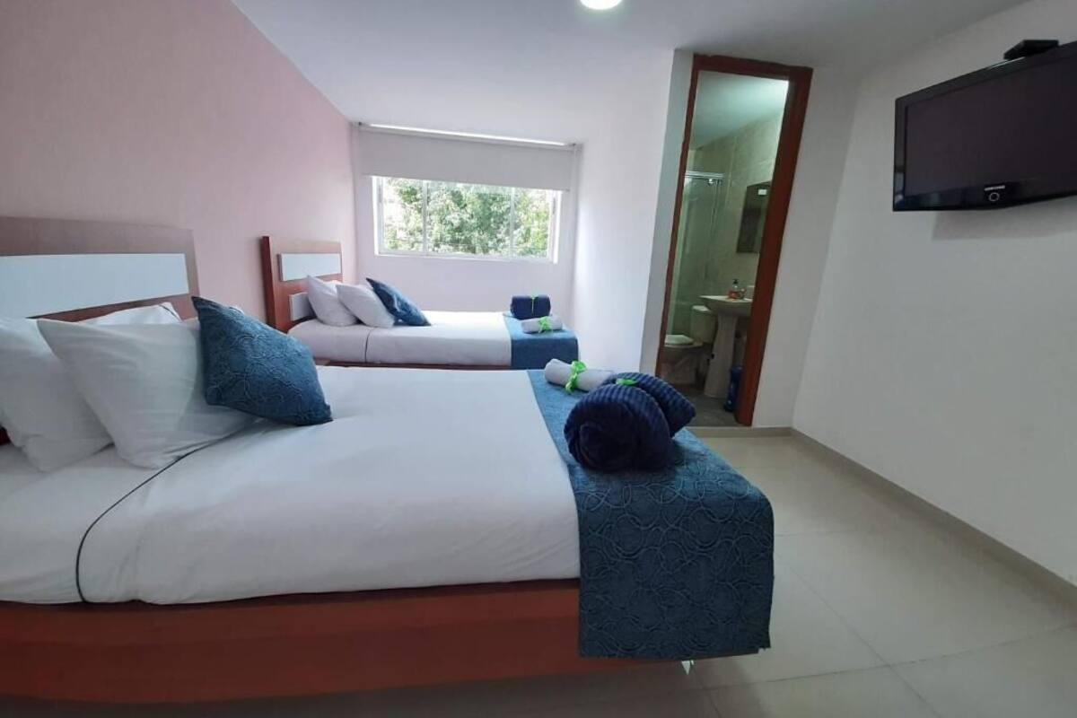 A hotel room with two beds, a TV, and a bathroom visible through an open door.