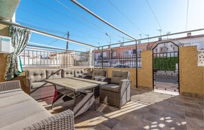 Relax on the patio with wicker sofas and a table, surrounded by a metal gate and wall, offering a view of the neighborhood.