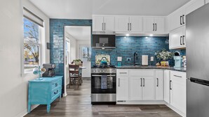 A modern kitchen with white cabinets, a stainless steel refrigerator, and a blue tiled backsplash. - Charming Cottage (Machesney Park)