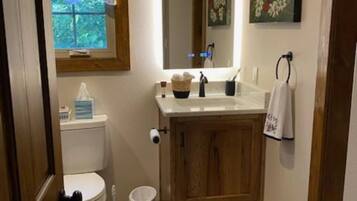 Un baño pequeño con inodoro, lavamanos y espejo.