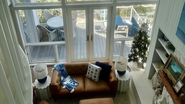 A living room with a large window overlooking a deck and ocean view.
