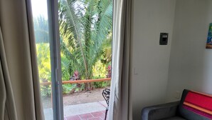 A room with a sliding glass door leading to a balcony with a view of greenery and a tiled floor. - Tiny Condo PB 5 at Vista Encantada! 1 Bedroom, kitchen, pool, incredible views!  (El Divisadero)