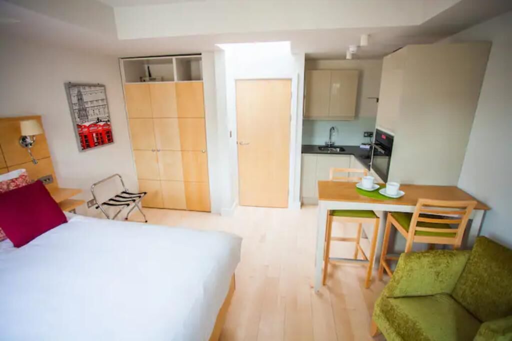 A compact room with a bed, a small kitchenette, a dining area, and a closet.