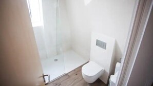 Un baño pequeño y moderno con cabina de ducha de vidrio, un inodoro y un lavamanos.