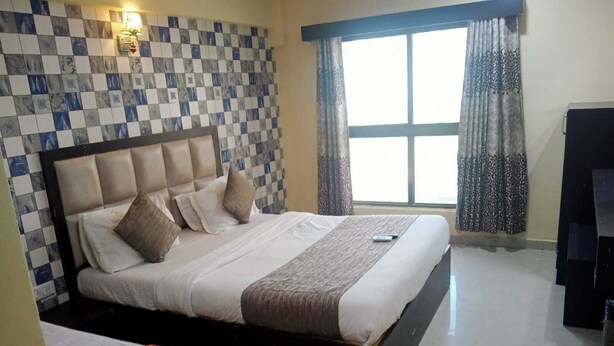 A hotel room with a bed, a small table, a TV, and a window with curtains.