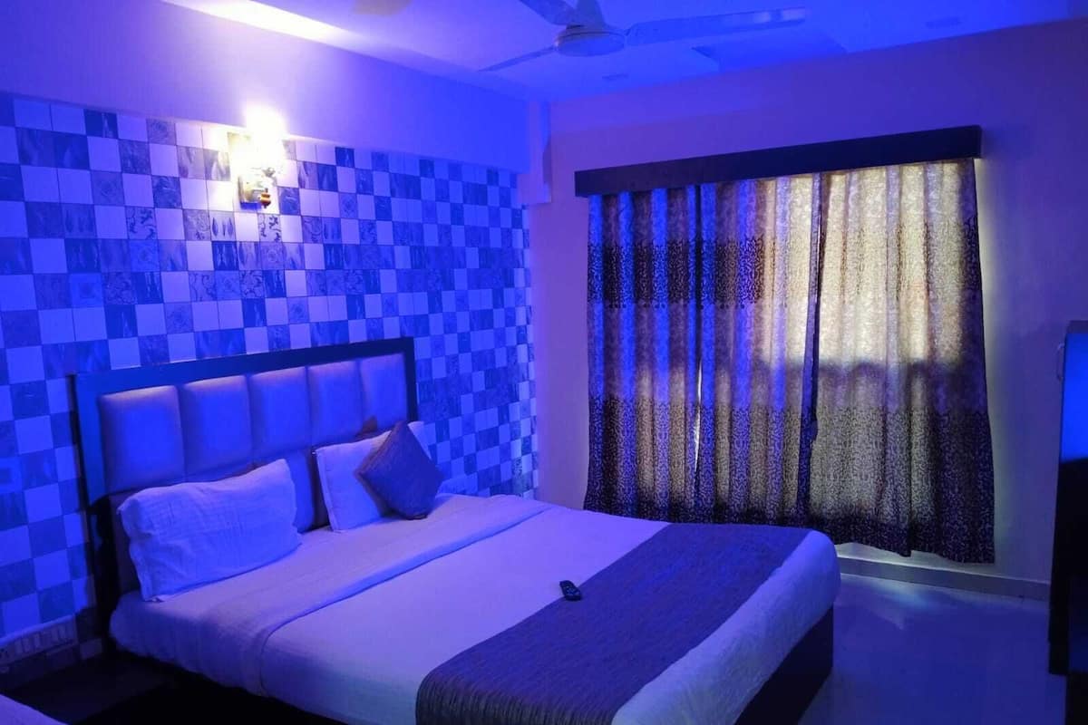 A bedroom with a checkered blue and white wall, a bed with white bedding, and a patterned curtain.