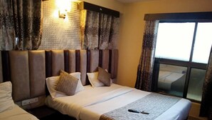 A hotel room with a large bed, a smaller bed, and a window with curtains.