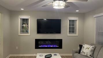 TV connectée, cheminée, livres, écrans d'ordinateur