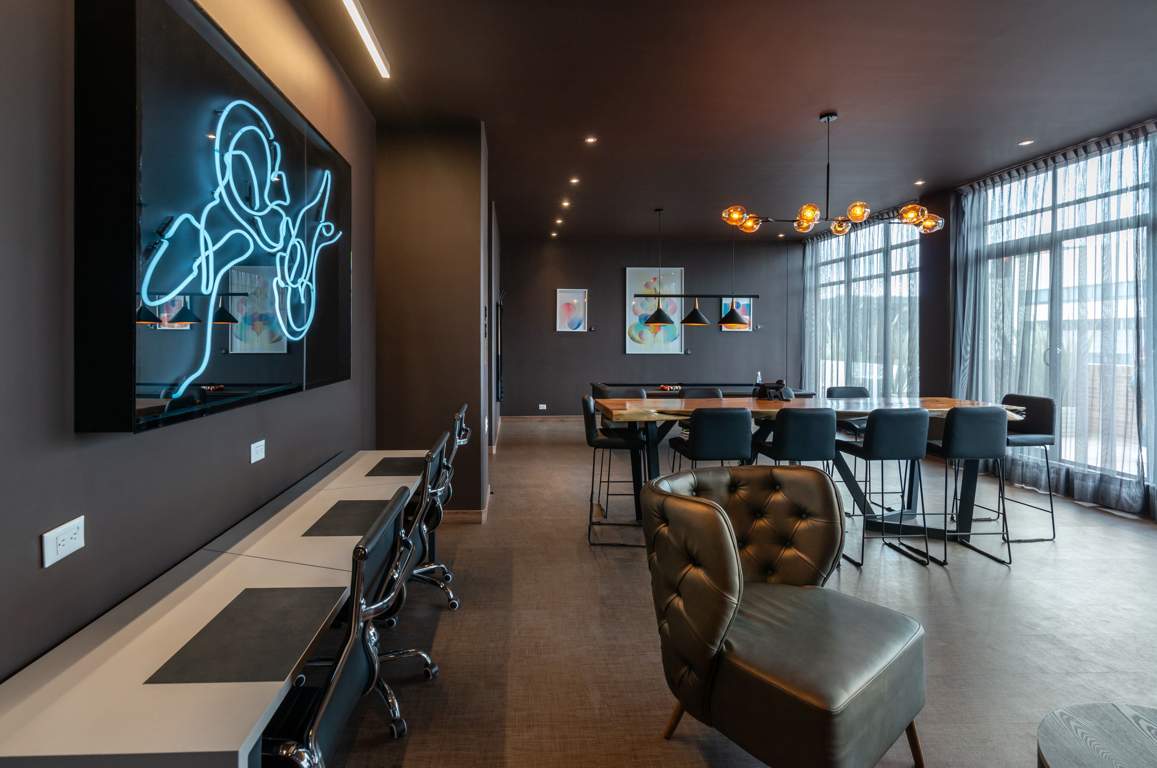 A modern conference room with a large table, chairs, and a neon art installation on the wall.