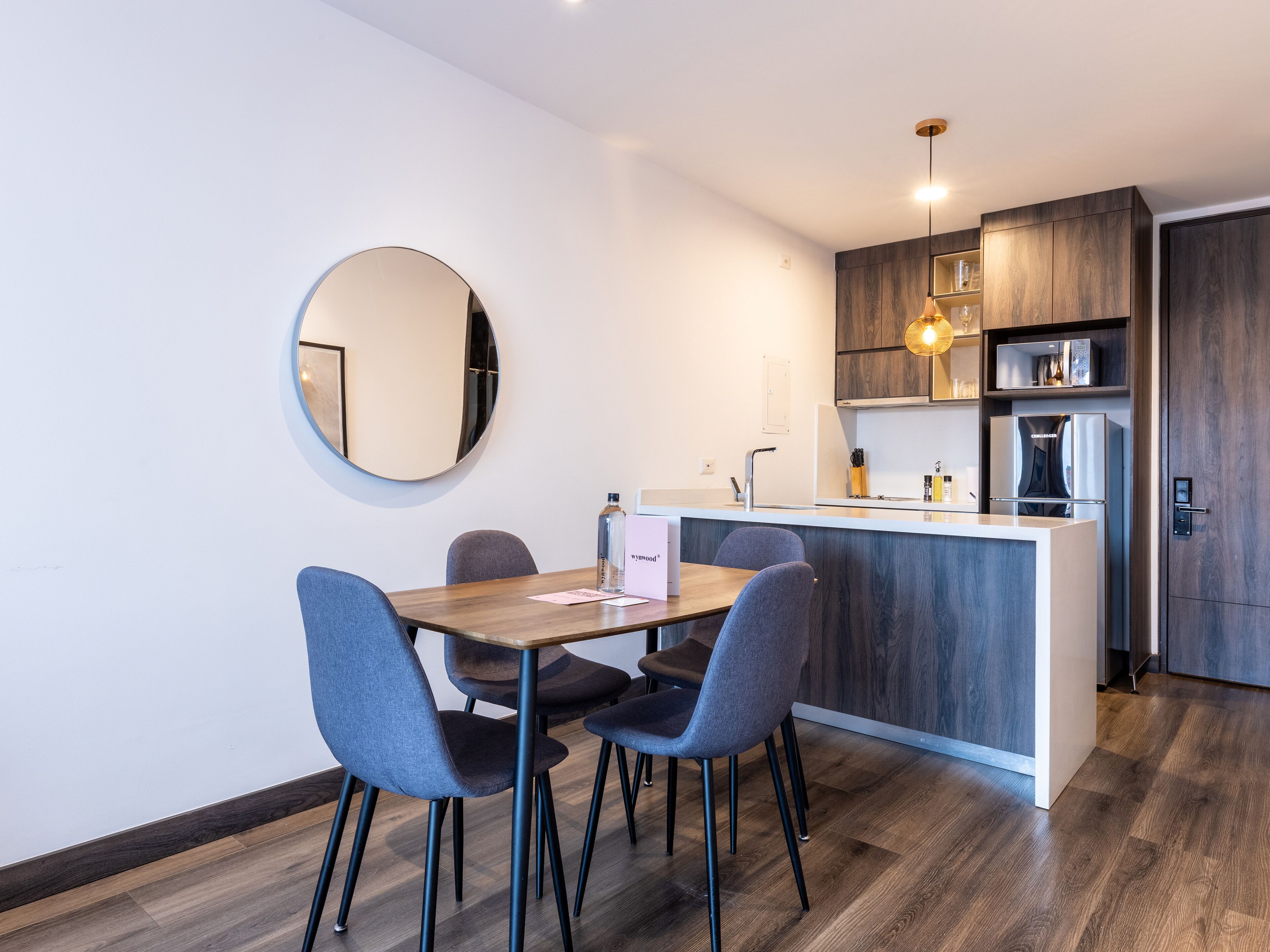 A modern kitchen with a central island, dark wood cabinets, and a round mirror on the wall.