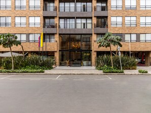 Um hotel com vários andares, fachada de tijolo, janelas amplas e uma entrada central.