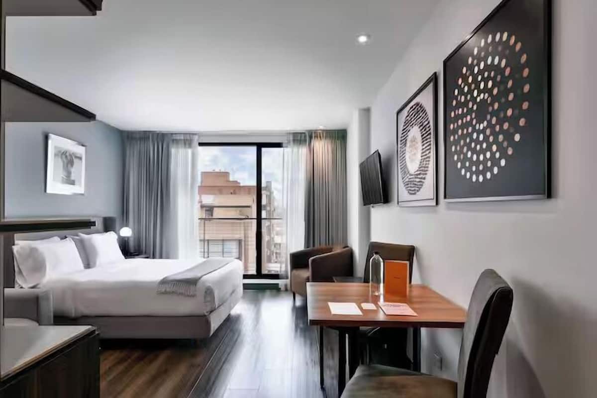 Una habitación de hotel con cama, escritorio, silla y vista a la ciudad.