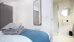 Hotellihuone, jossa on sänky, suuri peili, kylpyhuone, jossa on suihku, ja pesuallas.