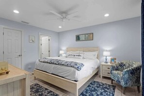 A bedroom with a bed, bedside tables, a chair, and a ceiling fan. - Saltwater Pool, Game Room, Mini Golf, 9 min to IMG (Bradenton)