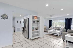 A modern living room with a white sofa, a coffee table, and a built-in white shelving unit. - Saltwater Pool, Game Room, Mini Golf, 9 min to IMG (Bradenton)