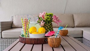 Ein Tisch mit Ananas, Zitronen, einer Blumenkomposition und einem Kokosnuss-Getränkehalter.