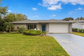 A single-story house with a garage, a front lawn, and a clear blue sky. - Saltwater Pool, Game Room, Mini Golf, 9 min to IMG (Bradenton)