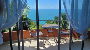 A balcony with a table and chairs, overlooking a coastal view. - 1 Bedroom Condo with Incredible Ocean View in Nayarit Jungle #404 (El Divisadero)